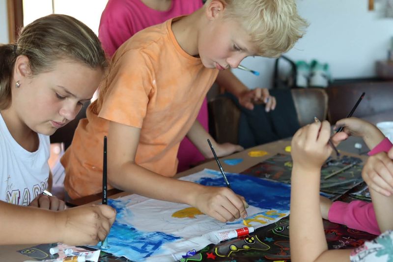 Děti malují u velkého stolu